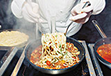 Chef cooking pasta dish in fry pan