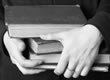 Picture of a pair of hands holding a stack of books.