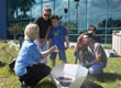 Picture of students studying a solar cooker.