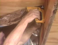 Photo: Close-up of man stapling radiant barrier to underside of roof decking