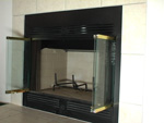 photo: black metal framed fireplace with opened glass doors without logs or ashes