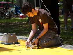 Photograph of students racing putting the model fuel-cell car on the starting line.