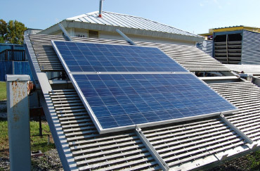 Photovoltaic system outside on rack with small water heating lab sitting in background.