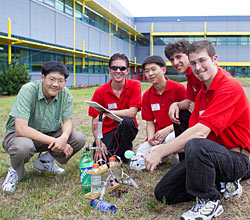 photo of students kneeling next to hydrogen refueling station made from plastic bottle and photovoltaic panel