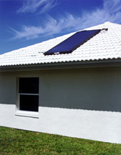 photo of side of house with solar water heating on white tile roof and large overhangs
