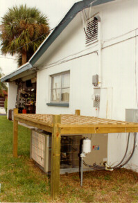 Trellis shading device built over the condenser at site #2. The packaged unit draws air through inlets on each side and exhausts air horizontally from the house.