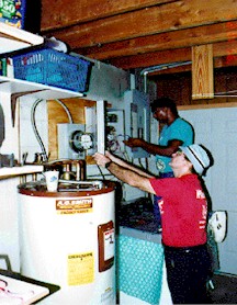 Picture of two technicians installing monitoring equipment near a hot water storage tank.